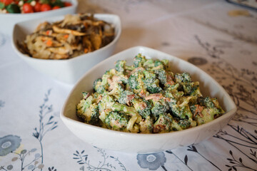Broccoli salad with cheese and mushrooms in white bowl on table
