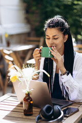 Woman in a cafe drinking coffee and working on laptop