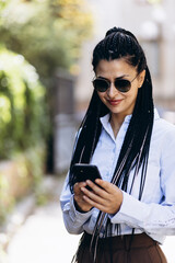 Business woman with braided hair talking on the phone outside the street