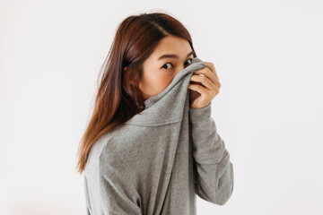 Asian Thai woman holding sweater, hiding and covering her face, shy and embarrassing, smelly...
