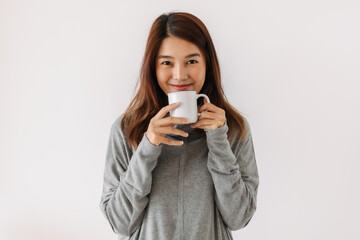 Happy asian woman holding and showing white cup with smiling face in winter, drinking hot water coffee, making warm, isolated over white background wall.