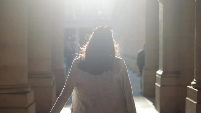 Beautiful woman with a white dress, walking  towards the light, on a bright summer day in Paris