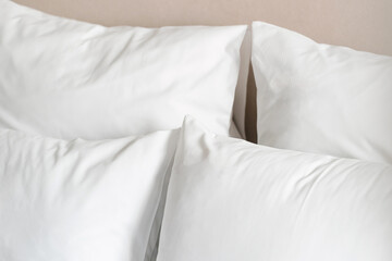 White bedding with two fluffy pillows on a neutral background in a cozy bedroom