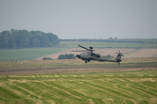 British army Boeing Apache Attack helicopter gunship AH64E AH-64E ArmyAirCorp hovering at low level over a grass meadow
