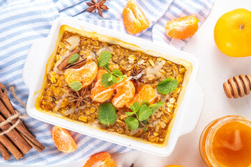 Tangerine or orange Creamsicle Baked Oatmeal, sweet healthy dessert with oats, fresh ripe tangerines and oranges, with creamsicle topping, honey and spices