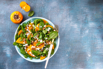 Sweet, savory delicious Persimmon autumn Salad with baby spinach leaves, cottage cheese and...