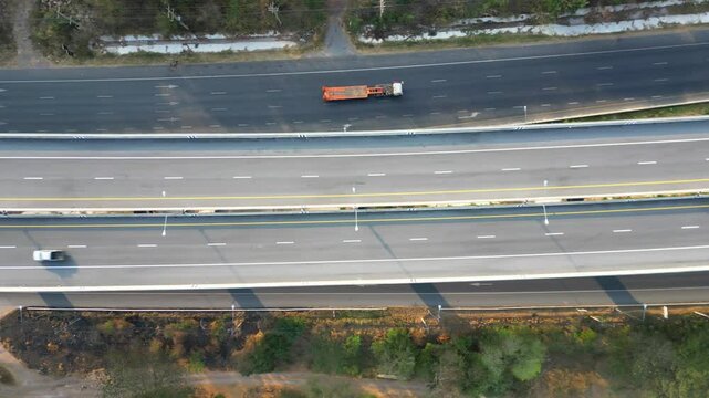 Top-down aerial view of a multilane highway with cars and trucks moving in opposite directions, highlighting modern road infrastructure.
