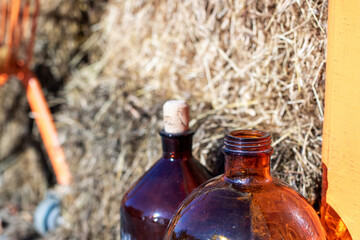 Two brown bottles with corks sit in front of a hay pile
