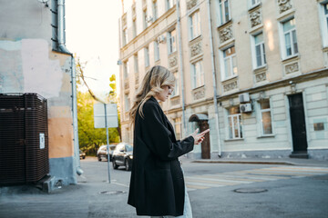 Obraz premium A Young Woman Strolling Through an Urban Environment While Engaged with Her Phone Device