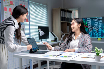 Two businesswomen discussing financial charts on a tablet in office