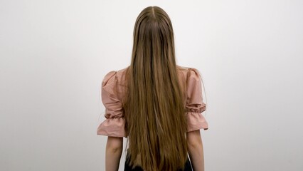 Fototapeta premium A girl with long blonde hair stands with her back to the camera.