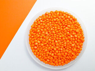 Orange masterbatch granules in a cup on a white and orange background.Color pigment carrier polymer...