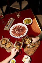Two hands clink their glasses of white wine during a romantic dinner.