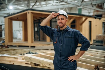 Fototapeta premium Looks far away. Male builder is at construction of wooden house