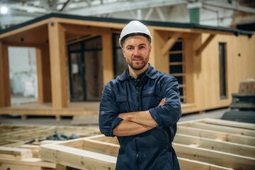 In white helmet. Male builder is at construction of wooden house