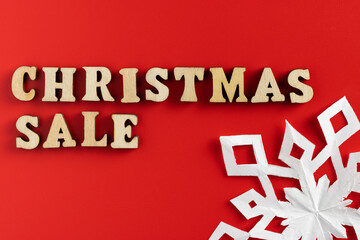 christmas sale wording with paper cut out snowflakes on red background. selective focus