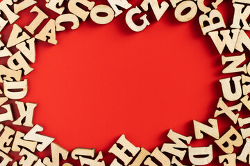 wooden letters scattered on red background. Empty space for copy space. selective focus.