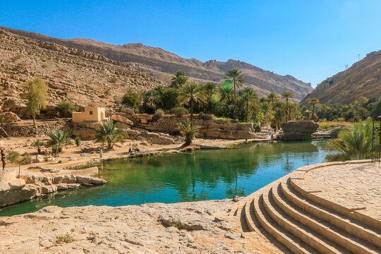 Exploring the stunning Wadi Shab Oasis in Oman with its refreshing waters and lush palm trees under clear blue skies