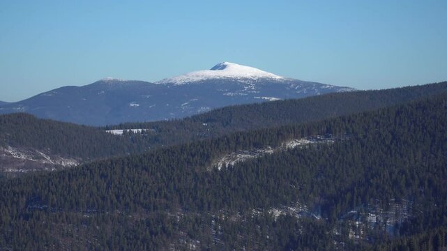 A scenic view of the snow-covered Babia G&oacute;ra mountain peak surrounded by vast winter landscapes in the Beskidy Mountains.