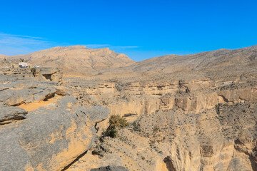 Stunning desert landscape of Oman showcasing rocky cliffs and clear blue skies under the midday sun