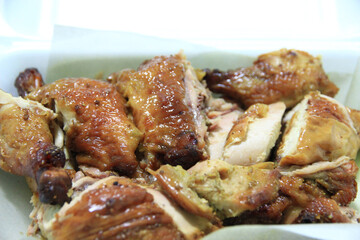 Grilled chicken cut into pieces ready to eat in a foam box.