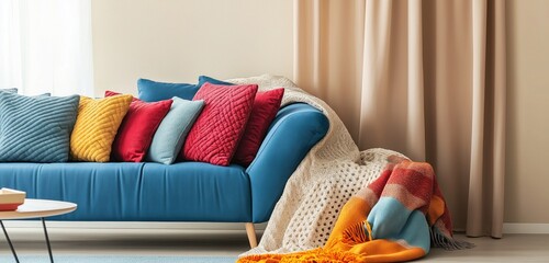 A cozy family room with soft beige walls and a bright blue sofa, complemented by colorful throw blankets and cushions that add warmth and personality to the space.