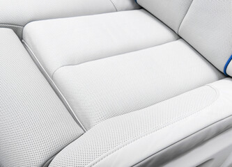 White leather interior of the luxury modern car. Perforated white leather comfortable seats with stitching. Modern car interior details.