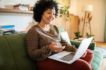 Smiling woman using laptop on the sofa at home