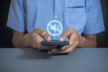 Man holding a mobile phone with mute sound or silent mode symbol