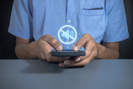 Man holding a mobile phone with mute sound or silent mode symbol