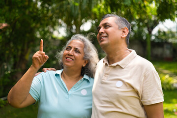 Indian couple in their fifties walking in the park, smiling and discussing with gestures