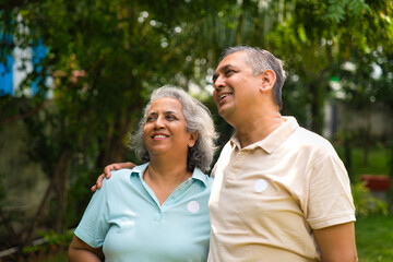 Indian couple in their fifties walking in the park, smiling and discussing with gestures