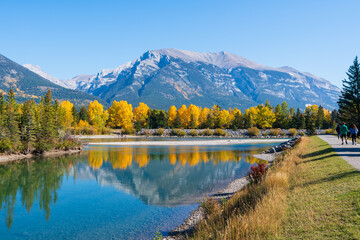Obraz premium People are walking along the Bow River riverside trail in autumn. Canmore, Alberta, Canada. Rundle Plante Lane.