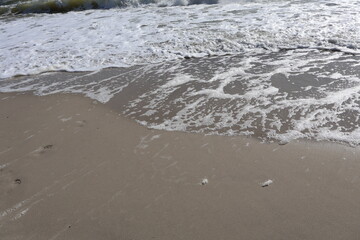 Soft Ocean Waves Gently Washing Over Sandy Beach with Foam
