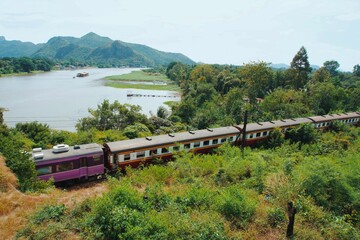 Naklejka premium A beautiful landscape view of a famous death railway in Kanchanaburi, Thailand that drive pass through the forest. The background of greenery Mountain View and river Kwai