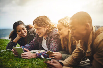 Fototapeta premium Happy, students and friends in park on tablet for online learning, social media and internet outdoors. Diversity, relax and men and women on digital tech for education, studying and college in nature