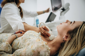 Side view. Woman is lying down and undergoing ultrasonic test of the thyroid gland