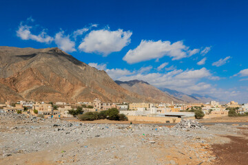 Mountainous landscape of Oman featuring traditional architecture and rugged terrain under a bright blue sky