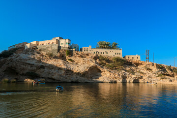 Exploring the scenic beauty of Oman with traditional boats near historical architecture at sunset