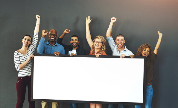 Happy, diverse and cheering marketing team with a blank card, poster or billboard with copyspace in studio on a grey background. A group of smiling business people celebrating and endorsing a product