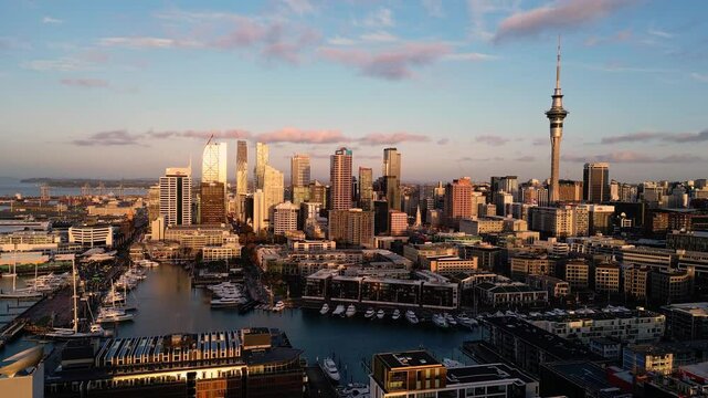 Auckland, New Zealand: Cinematic aerial drone footage of the sun sets over the Auckland business district skyline in New Zealand largest city. Shot with a forward and rotation motion.