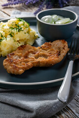 Pork chop served with mashed potatoes and cucumber salad.