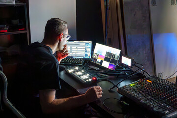 Video Director Managing Multiple Screens and Equipment in a Control Room During a Live Broadcast