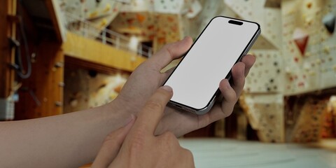 Caucasian White young male using smartphone with a blank white screen. Climbing, gym, indoor apps mockup. Vertical phone orientation