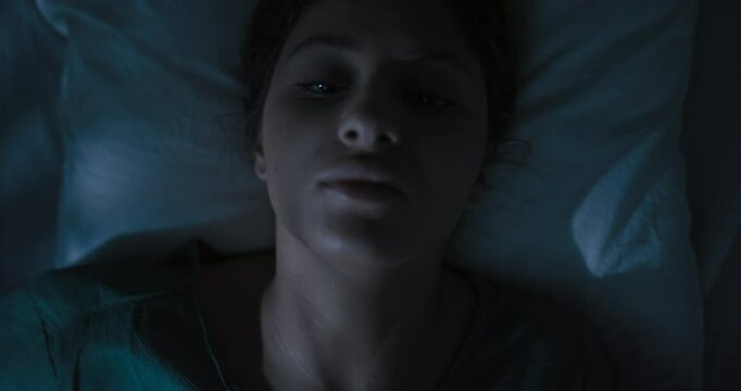 Exhausted female patient in hospital ward lying in bed preparing to asleep.