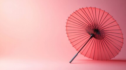 Traditional Japanese umbrella opened against a pink pastel background, space for text on the side