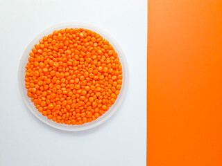 Orange masterbatch granules in a cup on a white and orange background.Color pigment carrier polymer in the plastics industry.