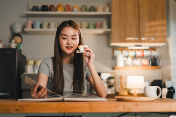 young woman enjoys cozy moment at home, reading book while sipping drink. warm, inviting kitchen setting enhances her relaxed expression