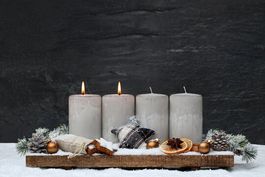 Adventsdekoration: Arrangement f&uuml;r den zweiten Advent : Dekoration mit vier grauen Adventskerzen und Weihnachtsschmuck im Schnee.
