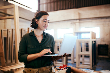 Industry, inventory and laptop with carpenter woman in workshop for craftsmanship, joinery or woodworking. Computer, online order and typing with confident person in warehouse for carpentry or trade